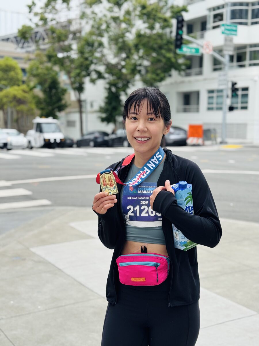 Dr. Joy Chen smiling with her finisher's medal after the 2025 San Francisco Half Marathon